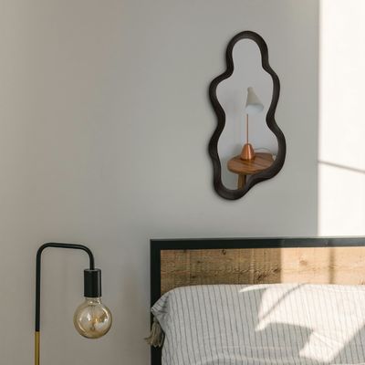 Красивое домашнее убранство Нерегулярное зеркало с черной деревянной рамой и современным убранством ванной комнаты